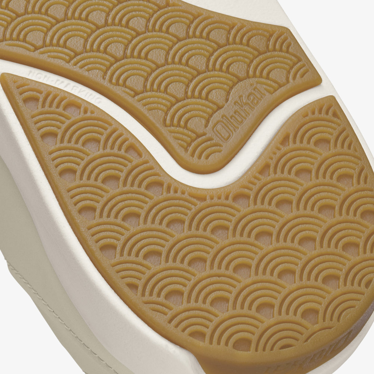 Tan and white shoe sole with repeating semicircle embossed pattern and brand text visible on upper section.
