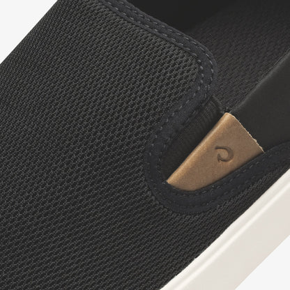 Black textured slip-on shoe with tan leather heel patch and white sole detail.