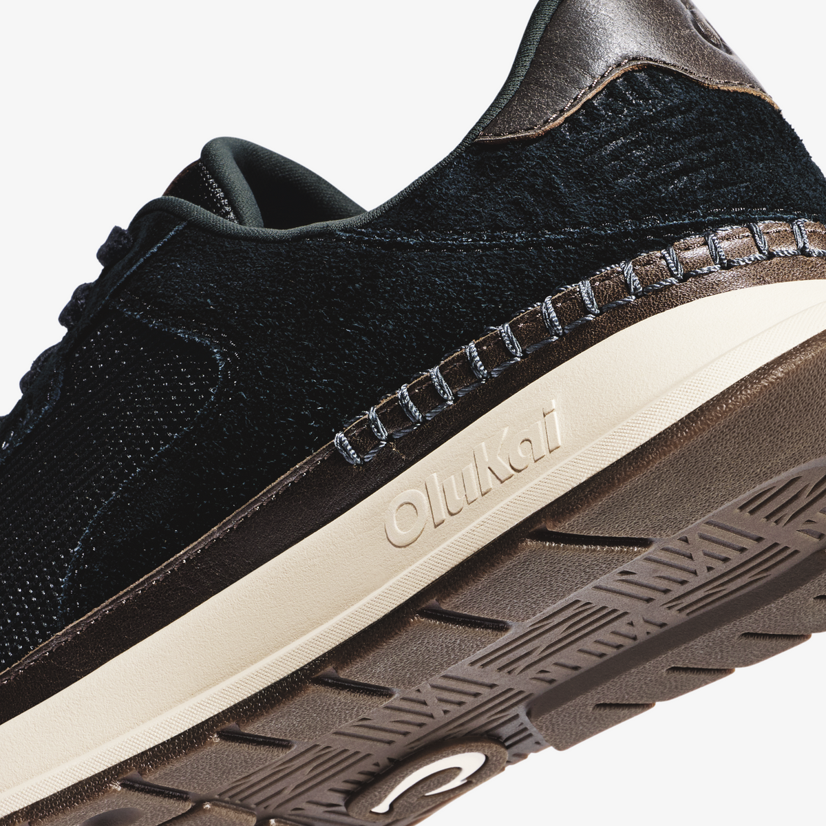 Black knit and leather sneaker with cream midsole and textured brown rubber sole, shown from side angle.