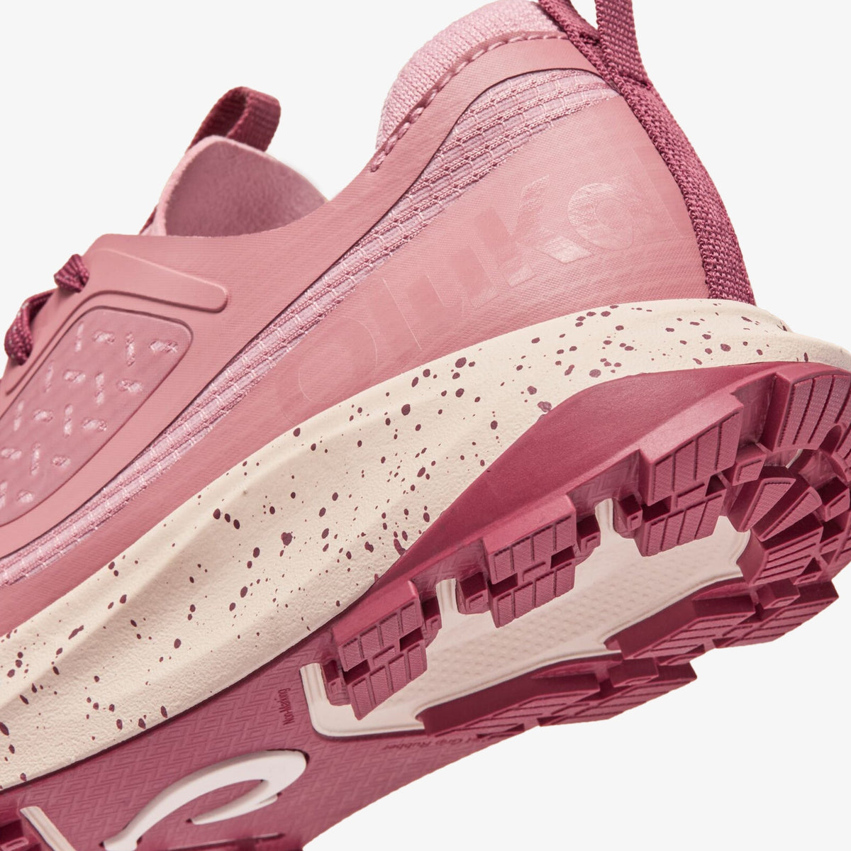 Coral rose athletic shoe with speckled cream midsole, textured upper, and burgundy rubber sole detail.