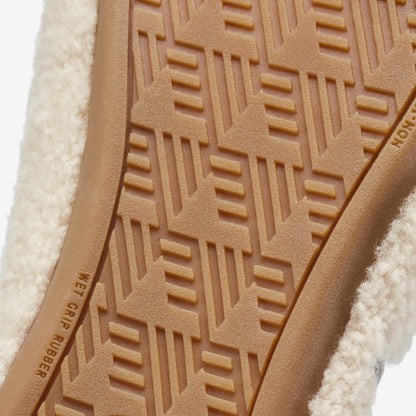 Tan leather sole with geometric tread pattern and cream-colored textile upper visible.