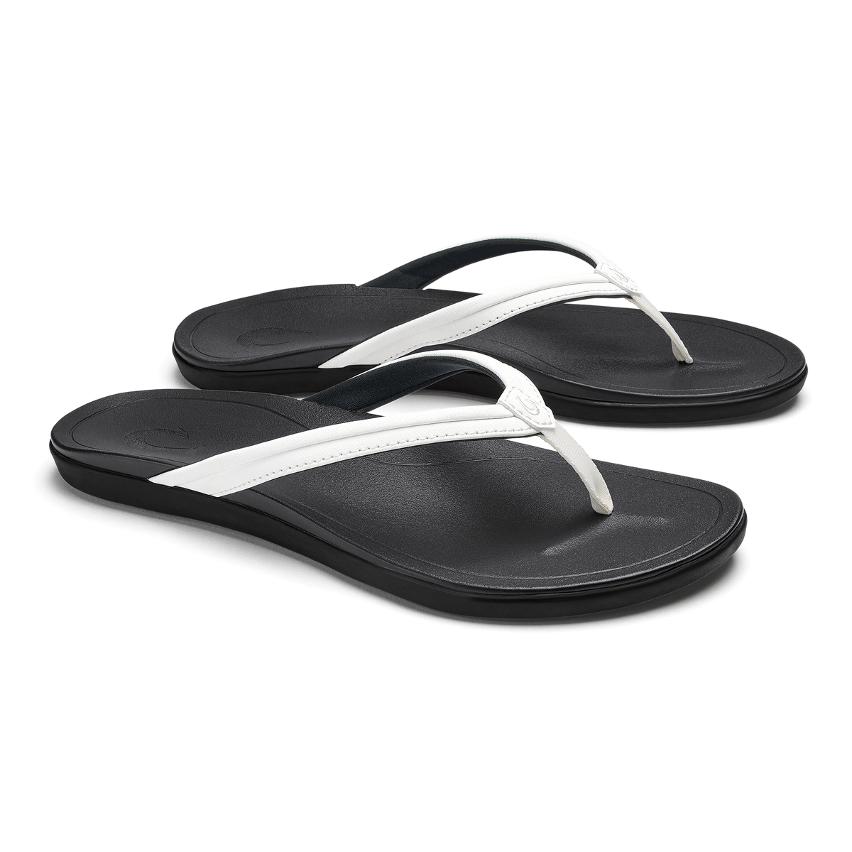 Pair of black flip-flops with bright white straps and black textured footbeds.