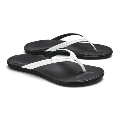 Pair of black flip-flops with bright white straps and black textured footbeds.