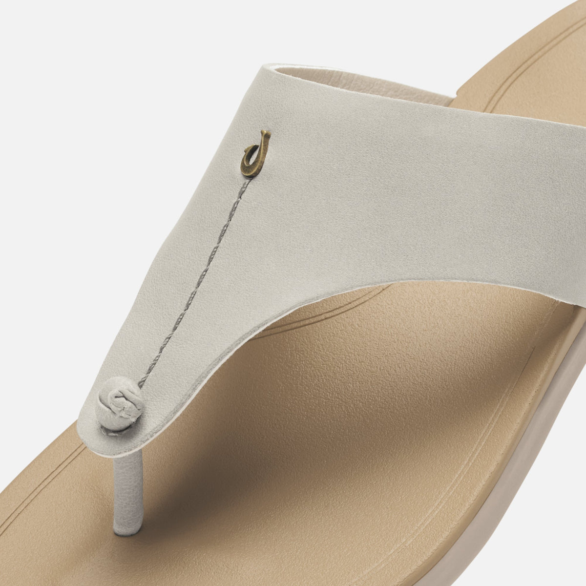 Cream-colored thong sandal with tan sole, metal loop detail, and adjustable cord closure.