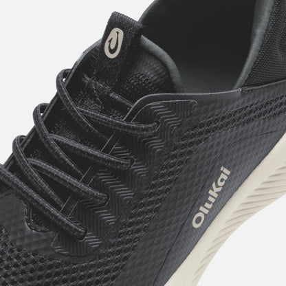 Black Kialoa sneaker with textured lava rock pattern, white sole, and cream-colored heel tab detail.